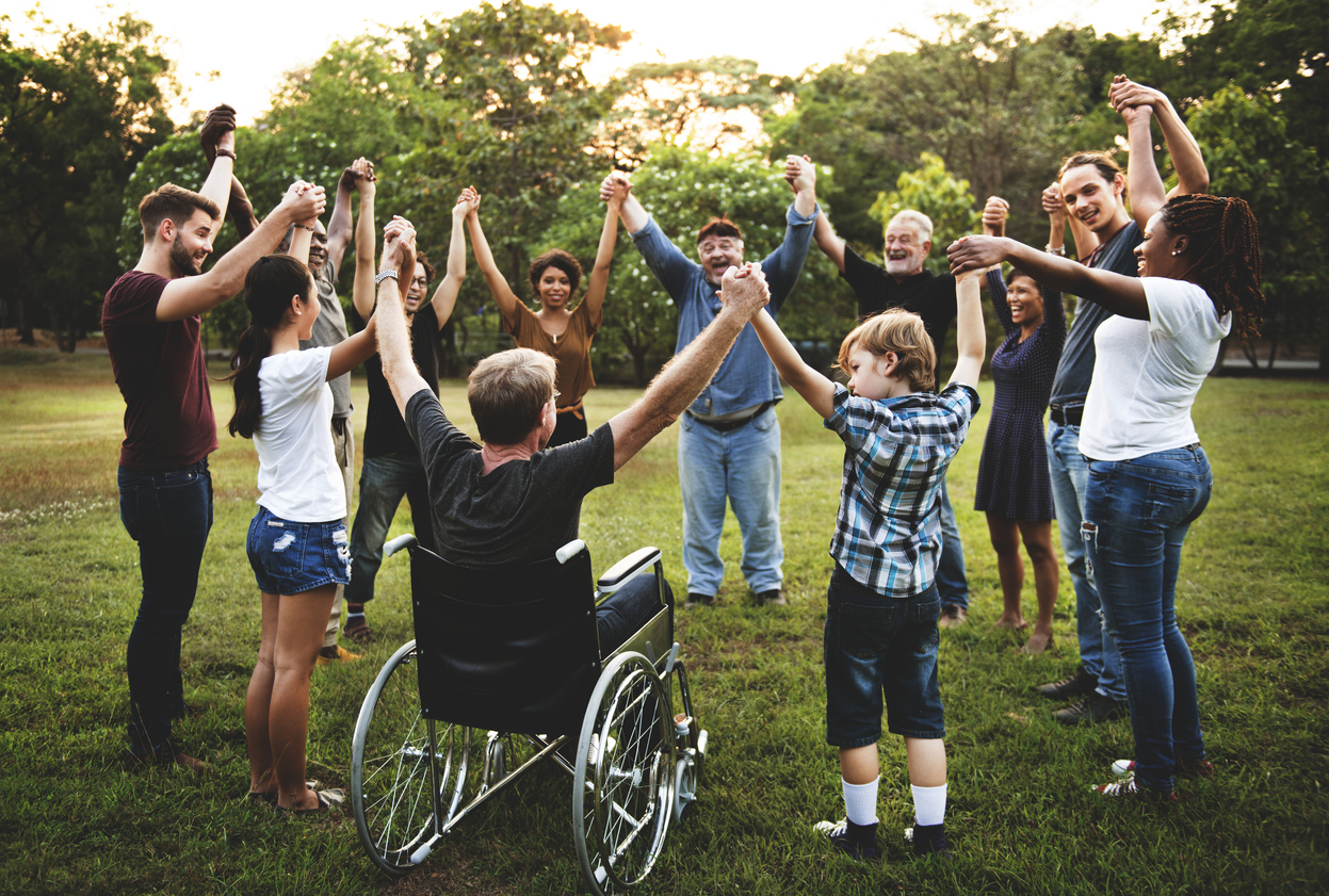 Diverse group of people holding hand with their arms raised in a circle outside